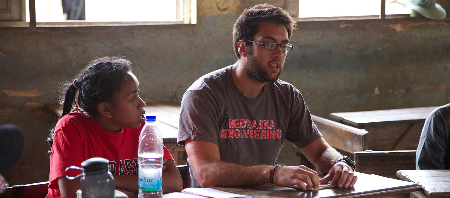 Nebraska Engineering Student sitting with in a classroom with a student during a mission trip