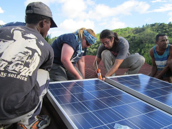 EWB-NU Madagascar Team installing a solar panel on a roof with the help of locals
